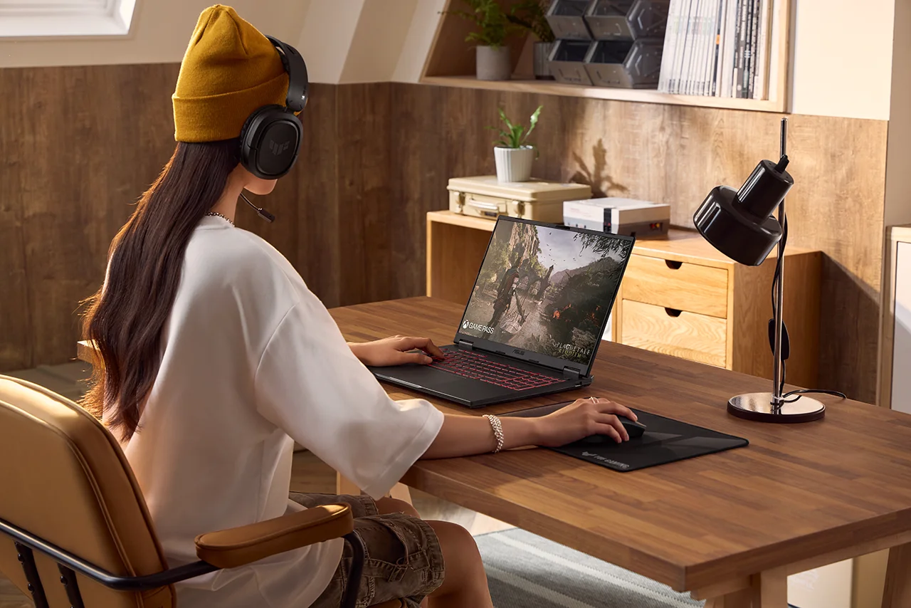 A young student using the ASUS TUF gaming laptop in a study room, highlighting its gaming performance and versatile use for study or play.