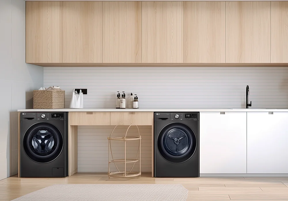 A matching, matte black LG front-load washer and dryer in a stylish laundry room with wooden cabinets, baskets, and soap bottles on a clean countertop.