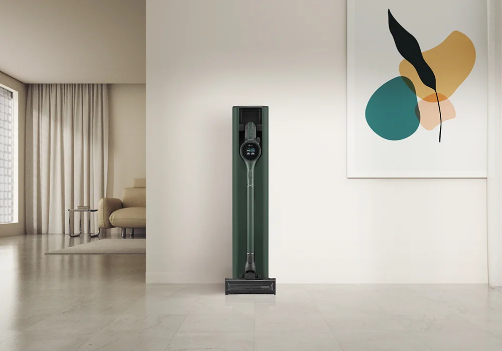 A forest green LG CordZero A9T handstick  vacuum cleaner in a sleek charging station, placed in a bright modern living room with light walls and minimalist decor.