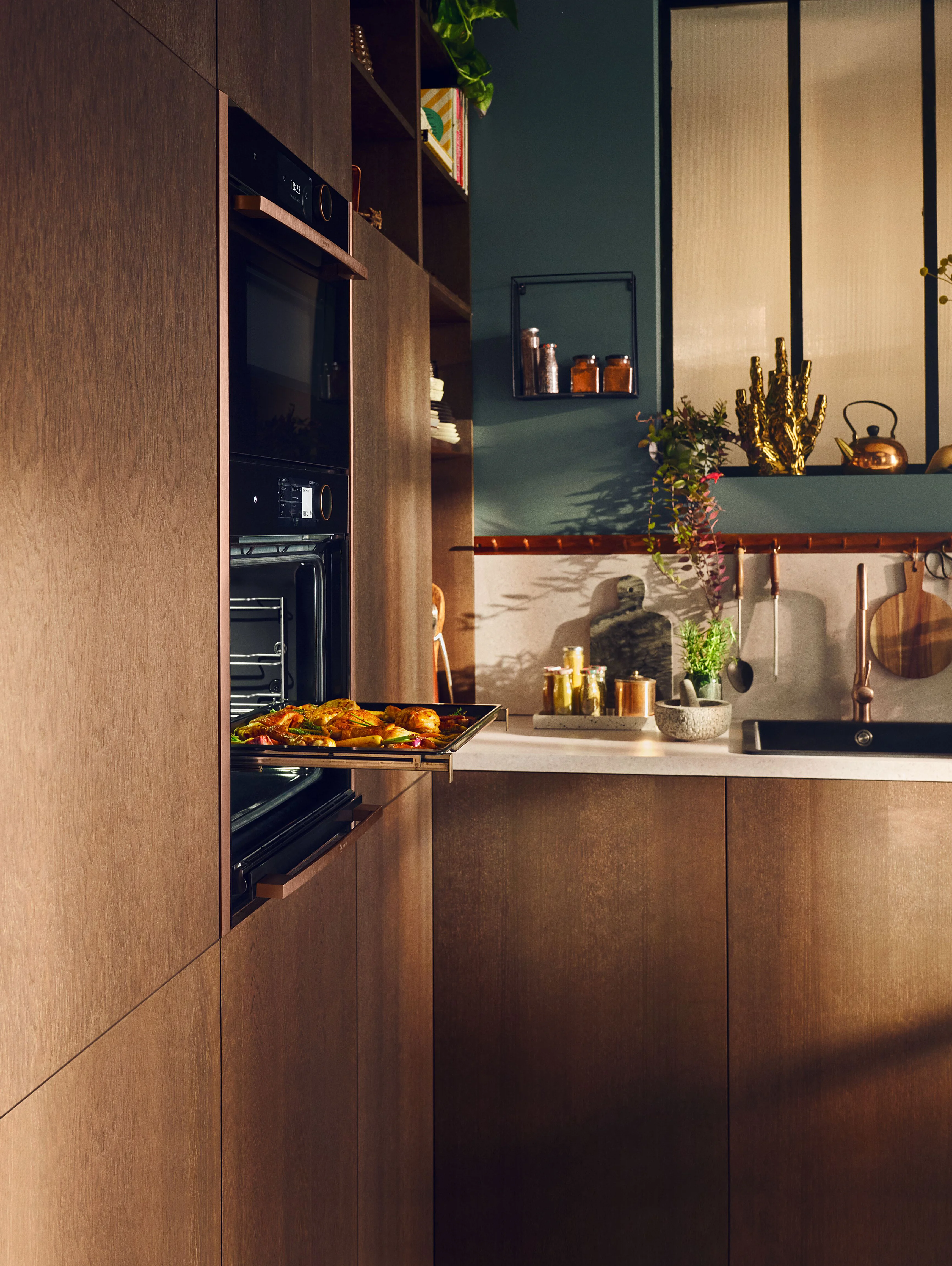 Modern kitchen with green cabinetry featuring a built-in slide and hide oven in the process of opening.