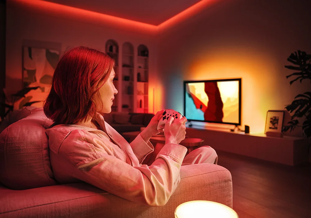 Immersive living room setup with Philips Hue smart light strips casting dynamic red and amber tones, enhancing the ambiance for gaming and entertainment.