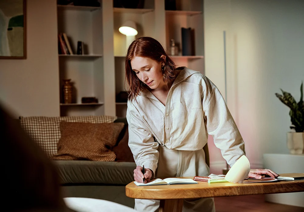 Cozy living room scene illuminated by a Philips Hue smart table light, creating a warm, customizable glow ideal for focused work or relaxed evenings.