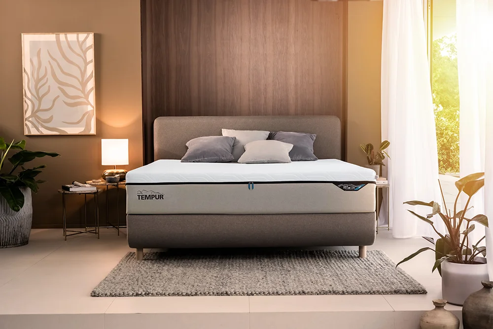 A tempur Pro Air mattress, on a bed frame in a modern bedroom with artwork on the wall and light coming through a window.