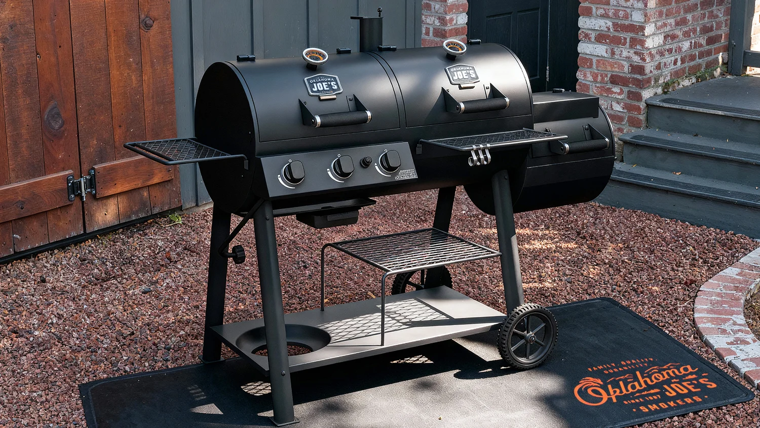 An Oklahoma Joe's Canyon Combo smoker grill with charcoal and gas chambers in a backyard.