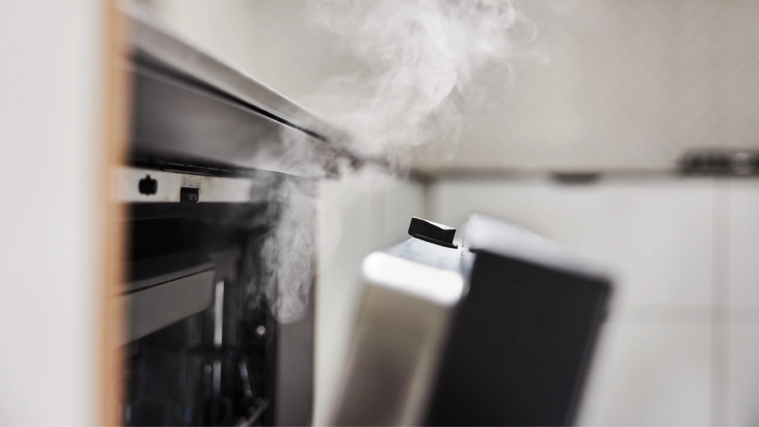 A Haier dishwasher door automatically opening at the end of a cycle with visible steam escaping from the interior, shown in a modern kitchen with tiled walls and soft lighting.
