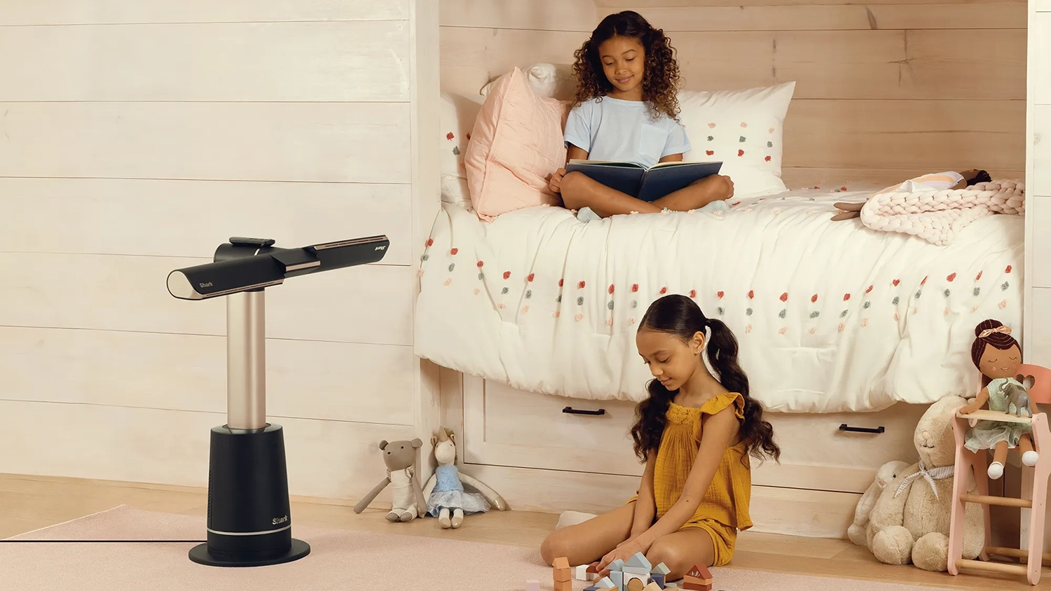 A Shark bladeless tower fan cooling a couple of kids in the bedroom, in a children's bedroom on a soft pink rug with plush toys on the floor, cooling a couple of kids in a bedroom.
