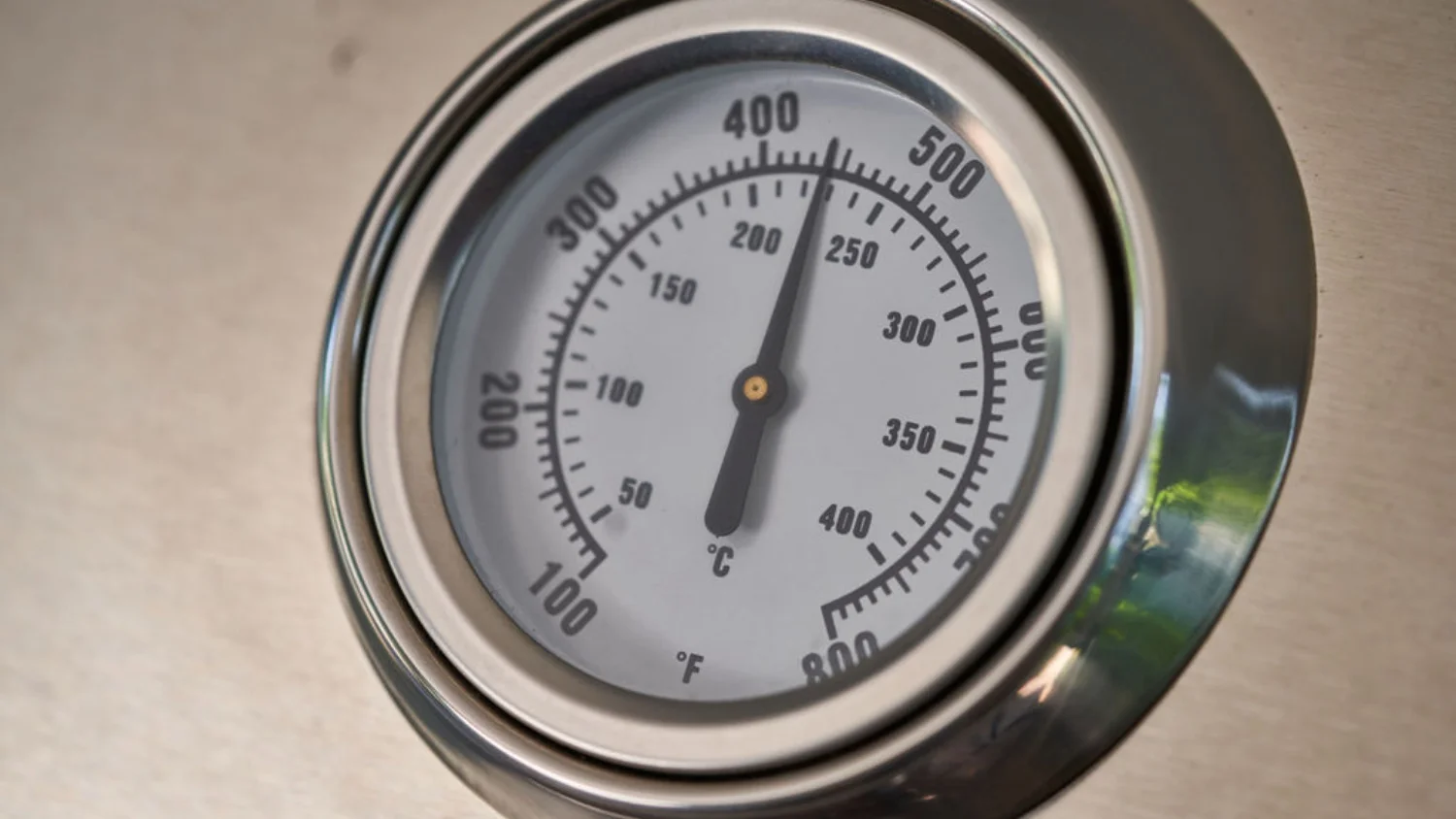 Close-up of the Crossray BBQ's built-in thermometer gauge displaying dual Fahrenheit and Celsius scales.