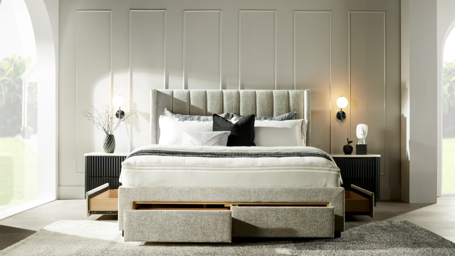 The queen size, light grey Orion bed frame with drawers, with all drawers open, in a brightly lit art deco style bedroom. There are art deco-style bedside tables with ornaments on either side of the bed.