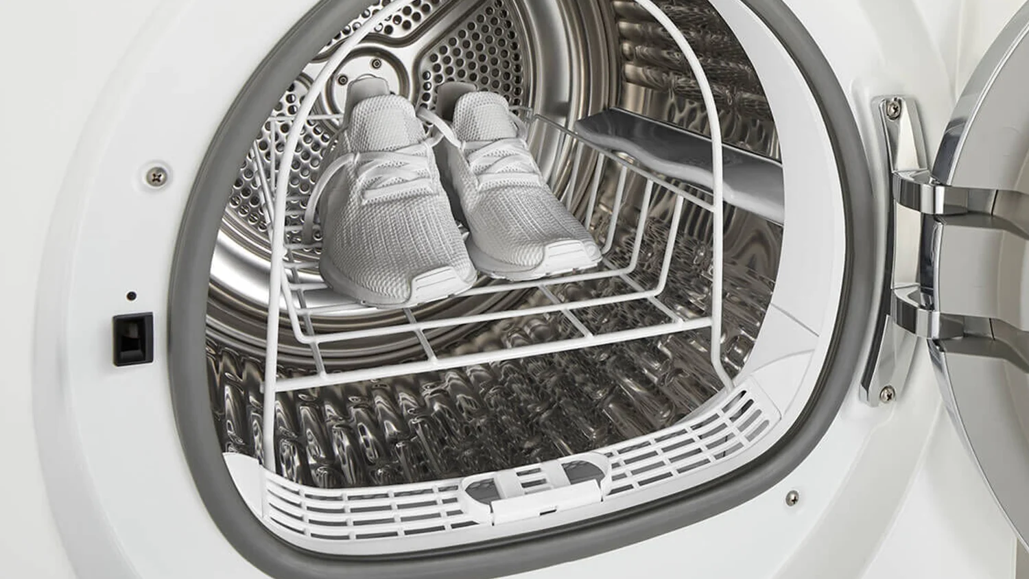 Interior of a Fisher & Paykel 9kg heat pump dryer with a drying rack holding a pair of white sneakers. The open door reveals the latch mechanism.