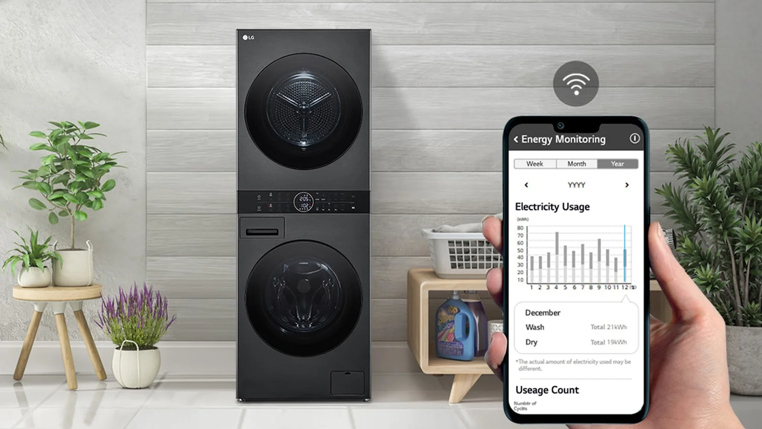 Modern laundry room featuring an LG washer and dryer unit. A hand holds a smartphone displaying an energy monitoring app.