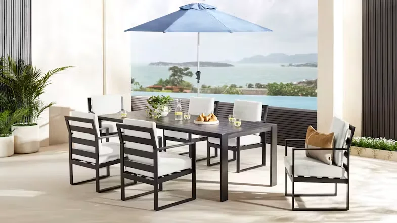 Atlas 7 Piece Outdoor Dining Suite on an outdoor patio with a blue umbrella