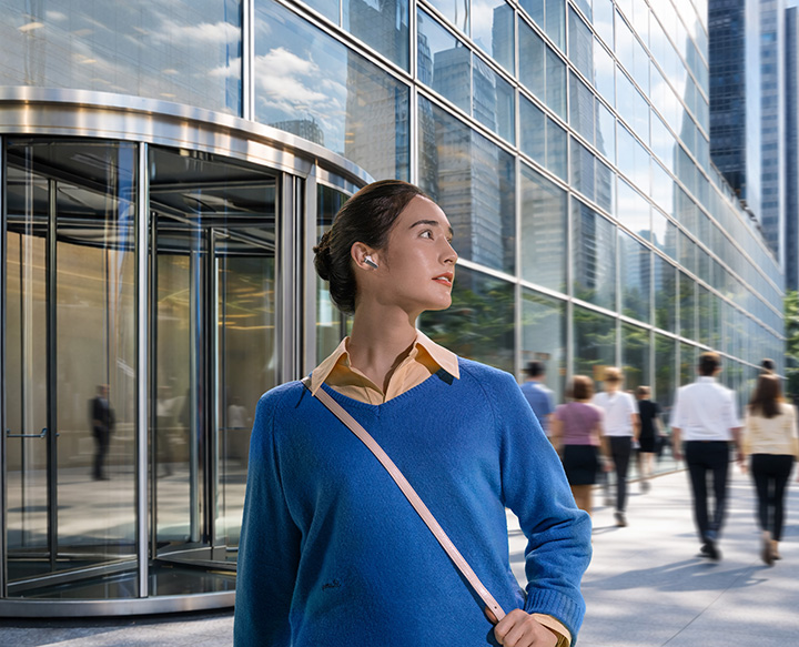 A woman using a single, white Galaxy Buds4.